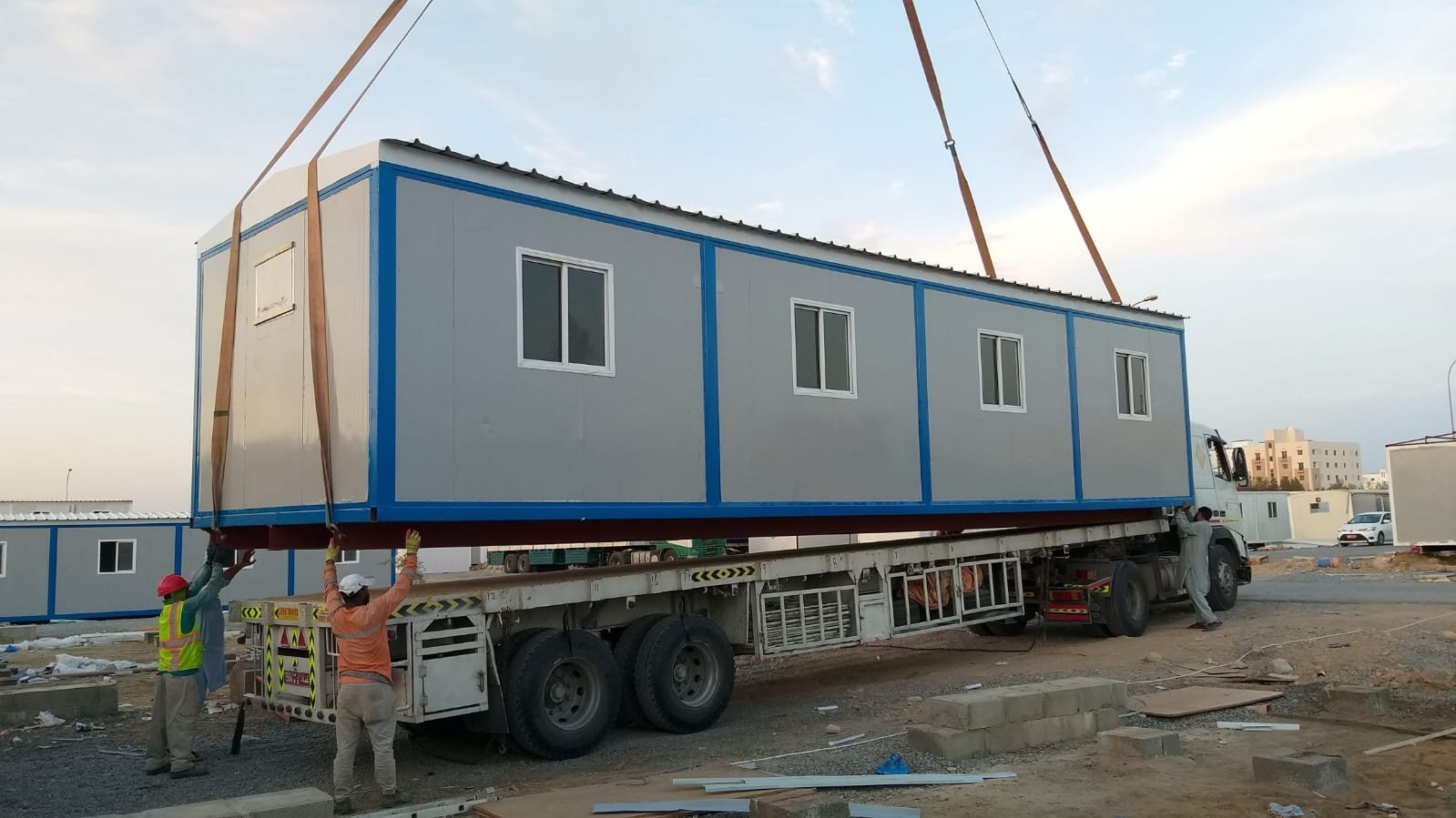 Crane lifting a sandwich panel cabin onto a truck for delivery